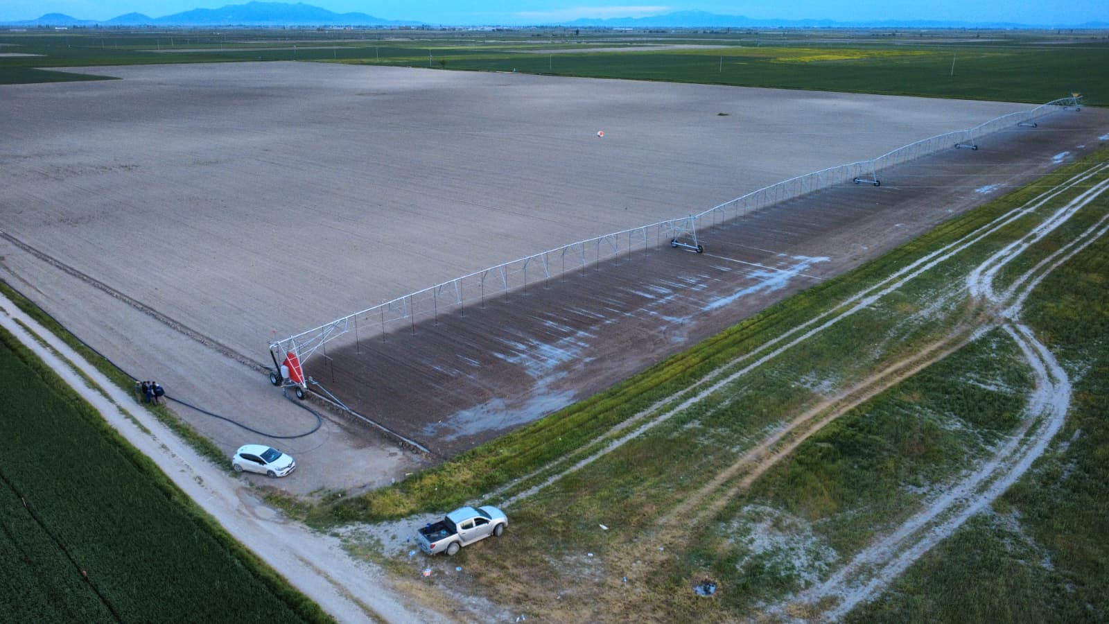 Linear pivot irrigation system in the field, fed by a hose at the drive cart